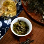 High angle view of freshly brewed tea with loose leaves on a bamboo mat, showcasing traditional tea preparation.