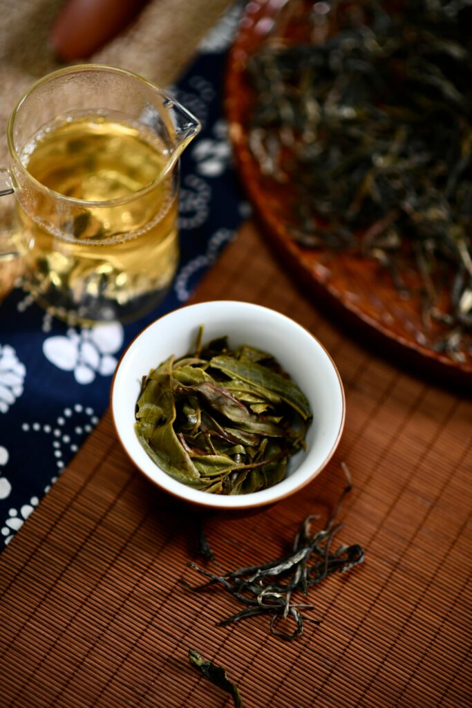 High angle view of freshly brewed tea with loose leaves on a bamboo mat, showcasing traditional tea preparation.