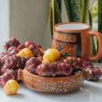 Olluco tubers with traditional Peruvian mug and ceramic bowl on a rustic table.